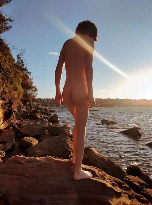 Rear view of boy standing beside a lake