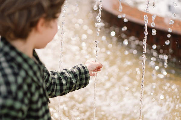 Boy reaching out to the stream from a fountain