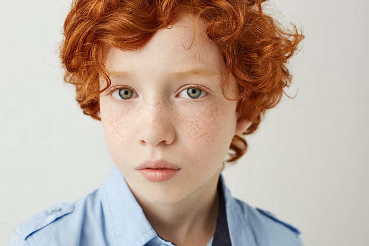 Head and shoulders shot of redhead boy looking at camera