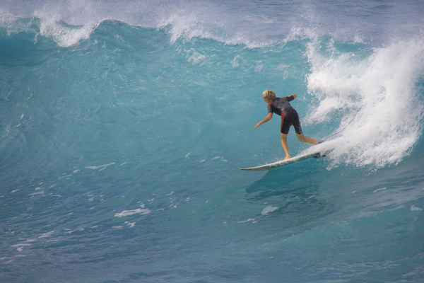 A teenage surfer glides down a wave