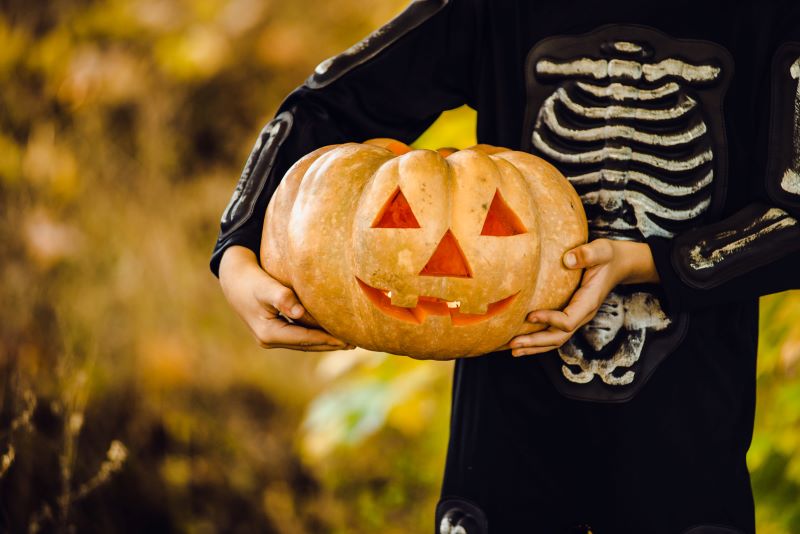 boy in costume holding Halloween pumpkin