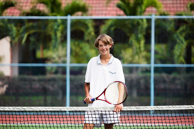 Young tennis player standing at net
