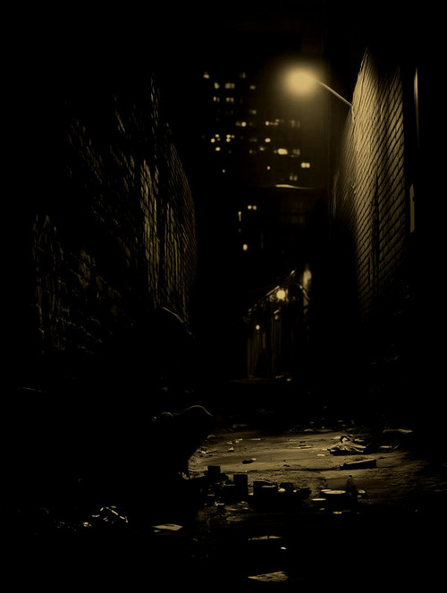 Person in hoody sitting in dark alley