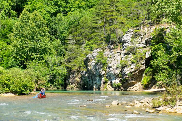 People paddling a canoe in a mountain stream