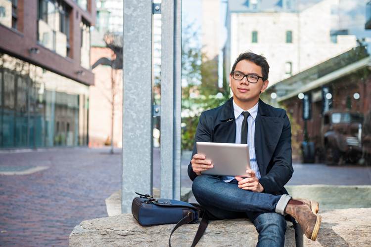 Handsome Asian man sitting with his computer, outside