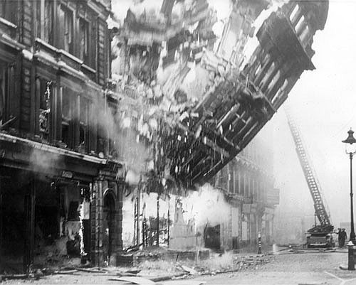 A building facade collapses into the street