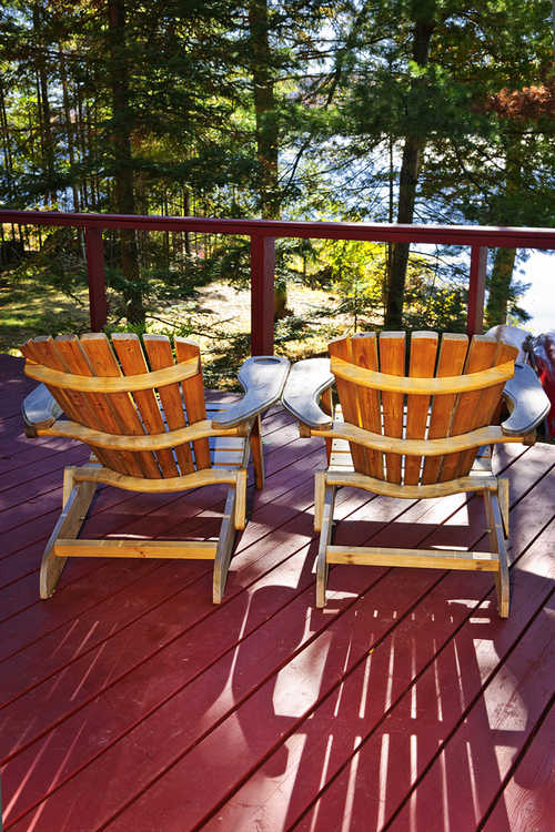 Two Adirondack chairs on deck ovrlooking forest
