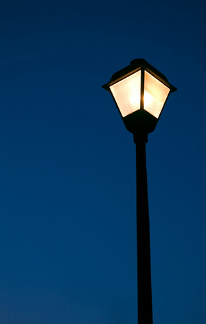 Street lamp alight against dark blue sky