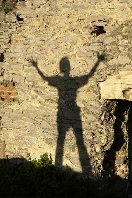Shadow on a stone wall of a person with arms outstretched