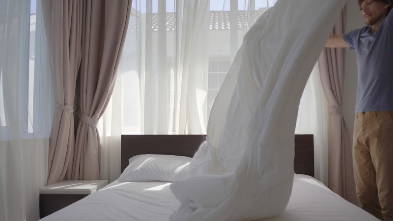 Young man making bed
