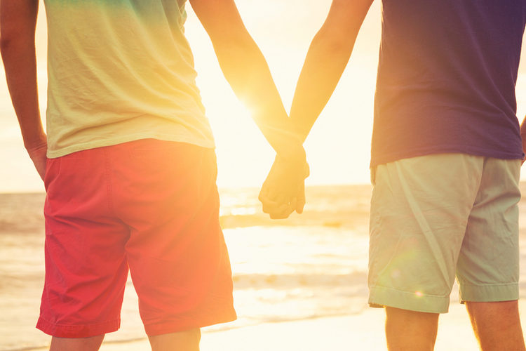 Two youn men holding hands watching sunset